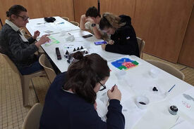 Photo de 4 personnes en train de dessiner sur une grande table dans une salle.