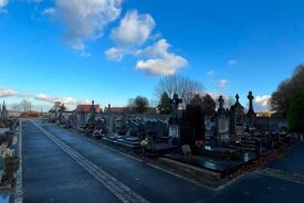 Photo de l'intérieur du cimetière avec l'allée centrale bordée de pierres tombales.