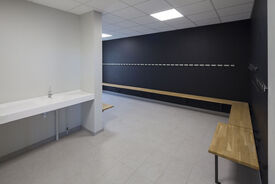 Photo de l'intérieur d'un vestiaire de la salle de sport. On voit à gauche de l'image un évier, et à droite le long des murs des bancs.