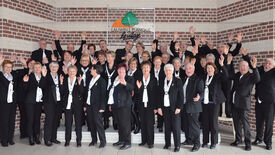 Photo posée des 55 choristes, habillés en blanc et noir.